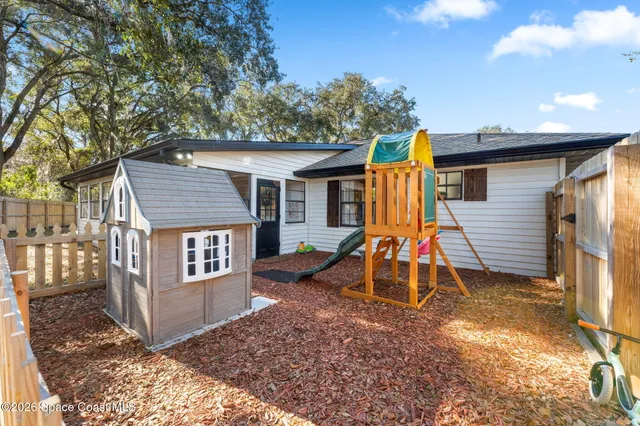 a view of a house with a yard and wooden fence