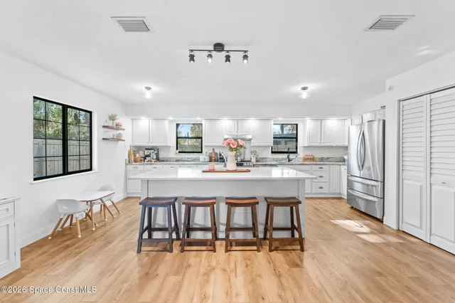 a kitchen with stainless steel appliances kitchen island granite countertop a refrigerator a stove a microwave oven a sink with island and chairs