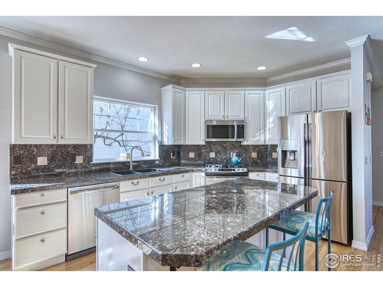 4944 Dakota Boulevard Boulder, CO 80304 - Photo 11 of 40 a kitchen with stainless steel appliances granite countertop a refrigerator a stove a sink and white cabinets with wooden floor