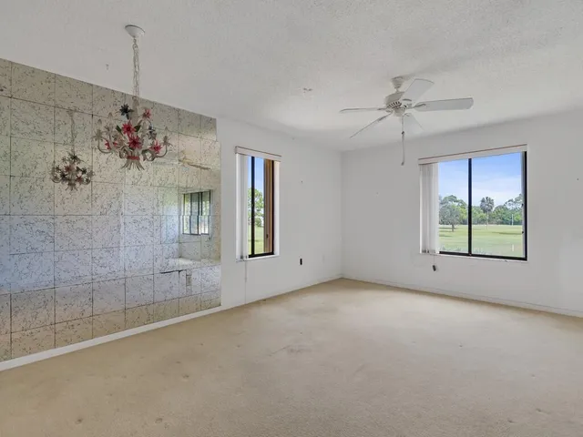 a view of a livingroom with a chandelier fan and windows