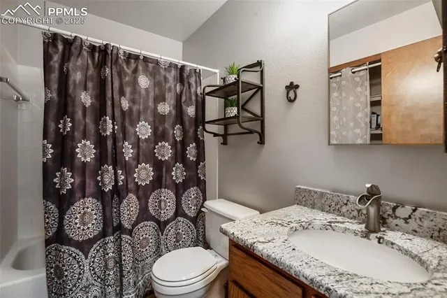 a bathroom with a granite countertop toilet sink and mirror