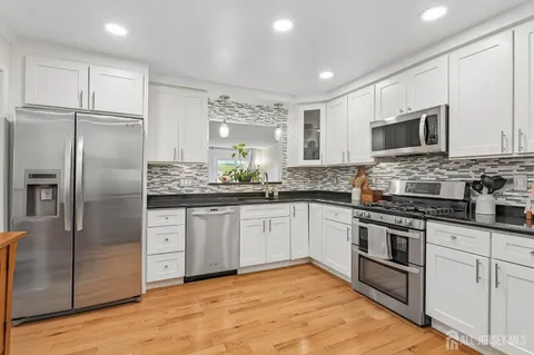 a kitchen with granite countertop a refrigerator and cabinets