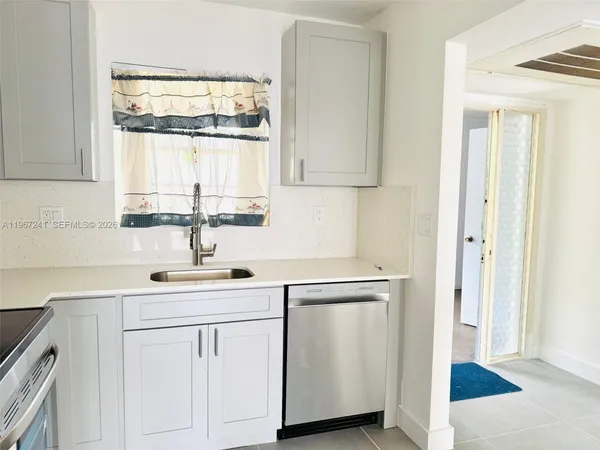 a kitchen with white cabinets and sink