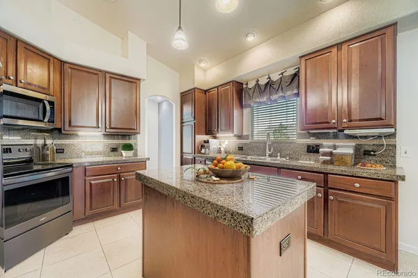 a kitchen with stainless steel appliances granite countertop a sink stove microwave and refrigerator