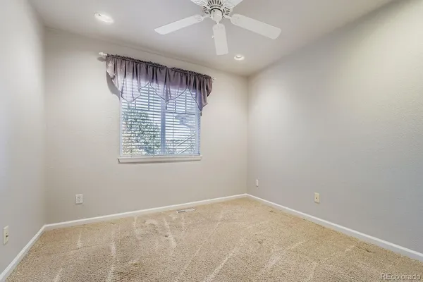 an empty room with windows and fan