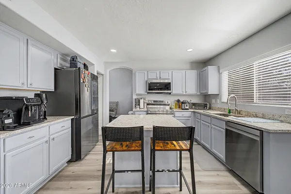 a kitchen with stainless steel appliances kitchen island granite countertop a refrigerator a stove top oven and white cabinets