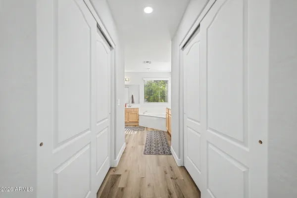 a view of a hallway with wooden floor and a bathroom