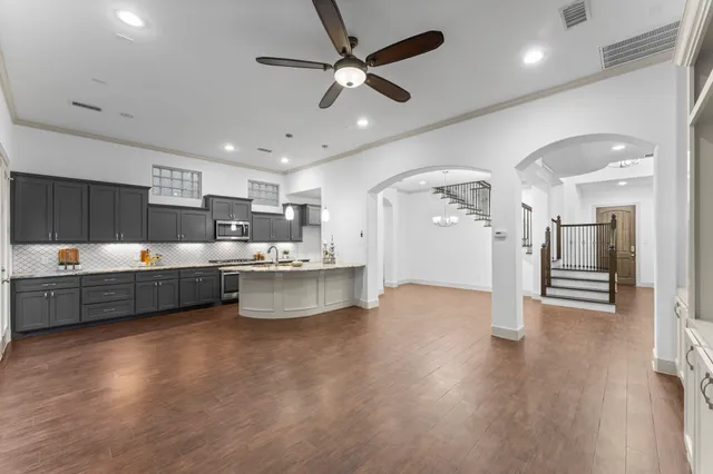 a large kitchen with a large counter top a sink stainless steel appliances and cabinets