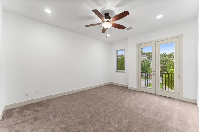 an empty room with a ceiling fan and windows