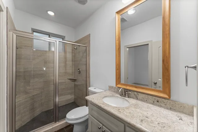 a bathroom with a granite countertop sink a toilet and shower