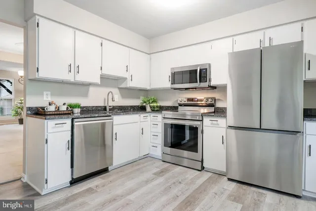 a kitchen with cabinets stainless steel appliances and wooden floor