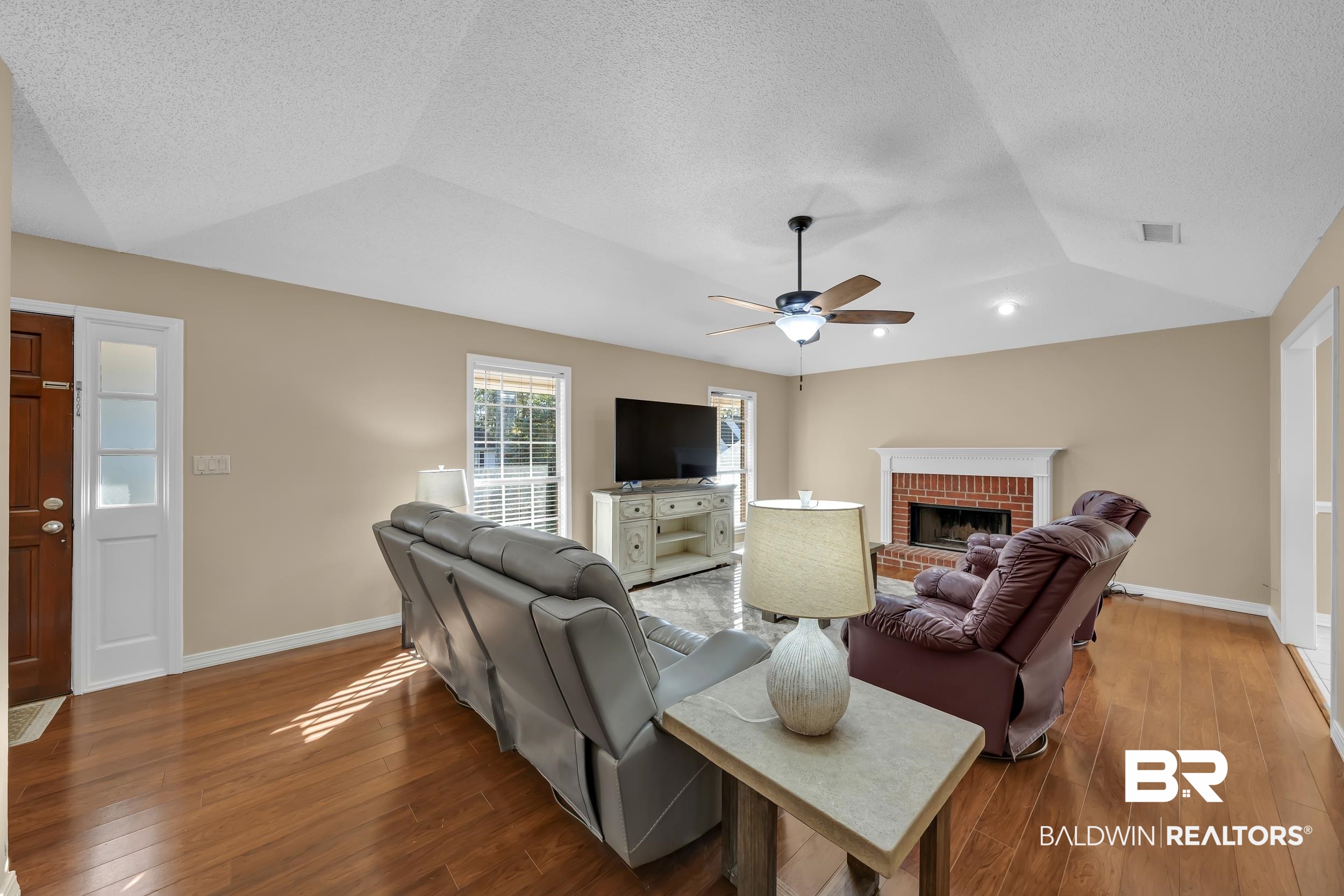 125 Dunbar Loop Daphne, AL 36526 - Photo 3 of 17 Living room featuring a brick fireplace, vaulted ceiling, hardwood / wood-style floors, a textured ceiling, and ceiling fan