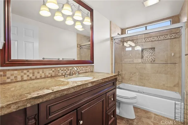 a bathroom with a granite countertop sink a toilet and shower