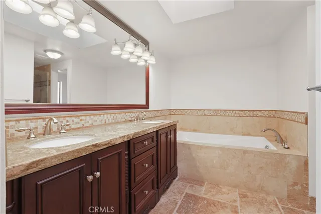 a spacious bathroom with a granite countertop bathtub a double vanity sink and a mirror