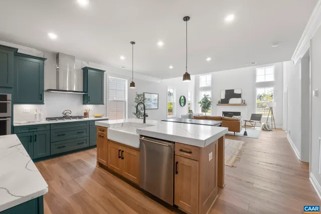 a kitchen with stainless steel appliances kitchen island granite countertop a sink a stove a refrigerator and island with wooden floor