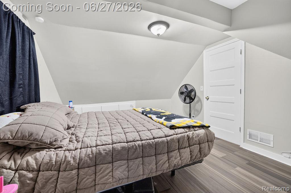 7715 Beech Daly Road Taylor, MI 48180 - Photo 20 of 21 Bedroom featuring angled ceilings, wood-finish flooring, a white paneled door, and an overhead flush-mount light fixture