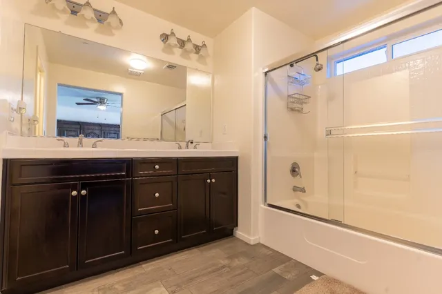 a bathroom with a granite countertop sink a mirror a shower and a bathtub