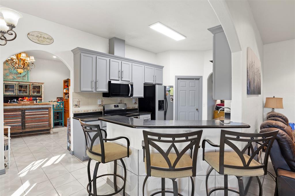 6524 Fair Road Kaufman, TX 75142 - Photo 11 of 30 a kitchen with stainless steel appliances a table chairs refrigerator and microwave