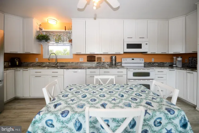 a kitchen with stainless steel appliances granite countertop a sink a stove a microwave a dining table and chairs with wooden floor