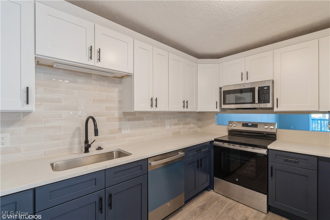 3725 Mayfield Road Cleveland Heights, OH 44121 - Photo 7 of 16 Kitchen with white cabinetry, sink, light hardwood / wood-style floors, and appliances with stainless steel finishes