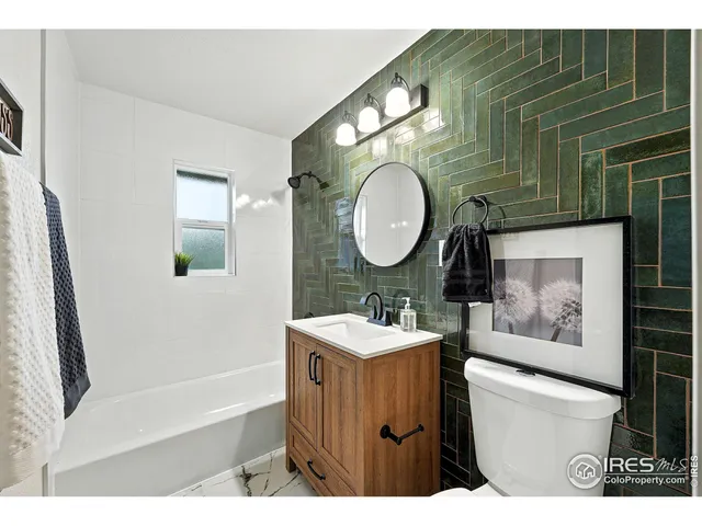 a bathroom with a toilet sink vanity tub and mirror