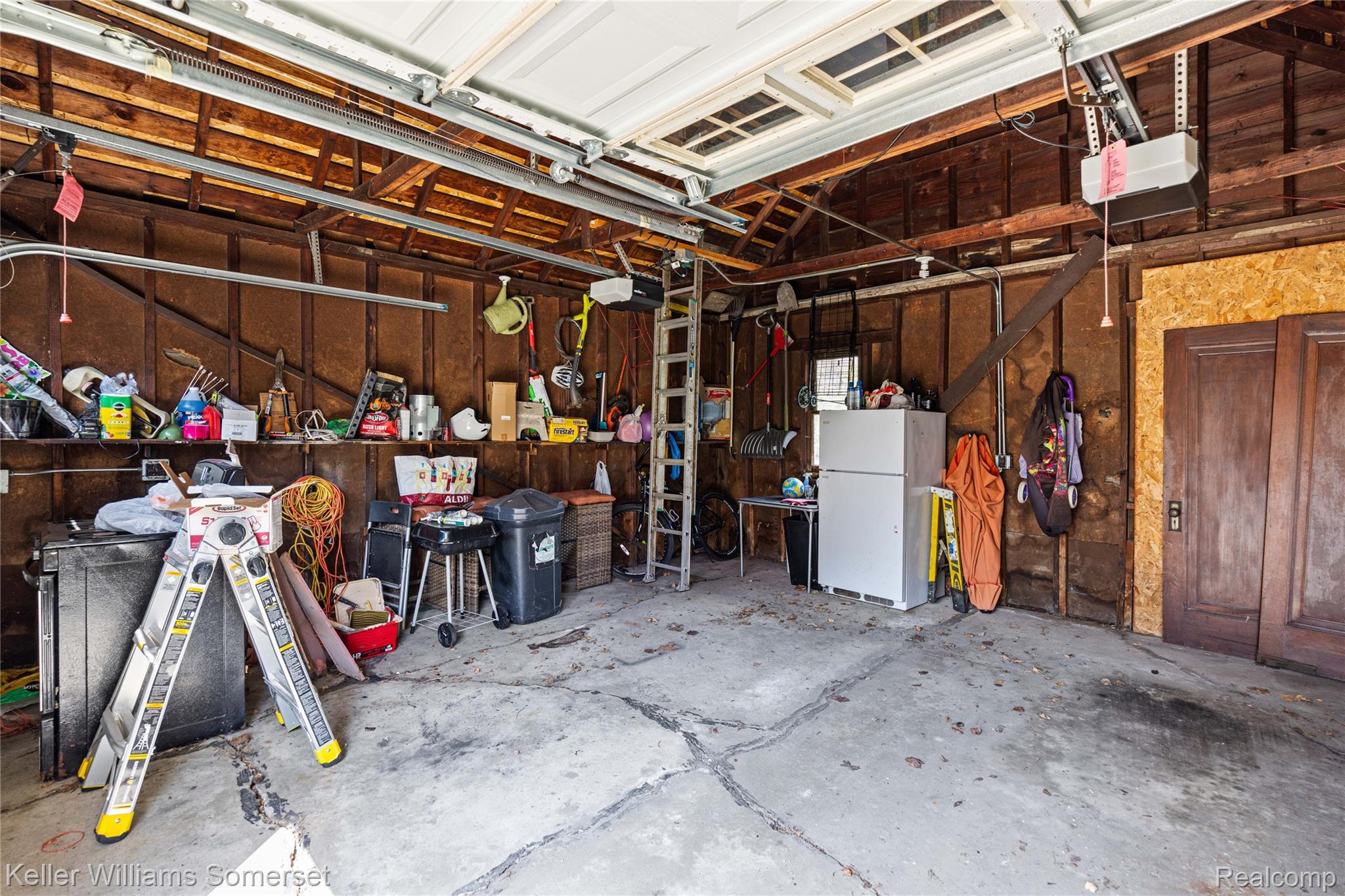 15 Miami Road Pontiac, MI 48341 - Photo 53 of 68 Garage featuring freestanding refrigerator, a garage door opener, and wood walls
