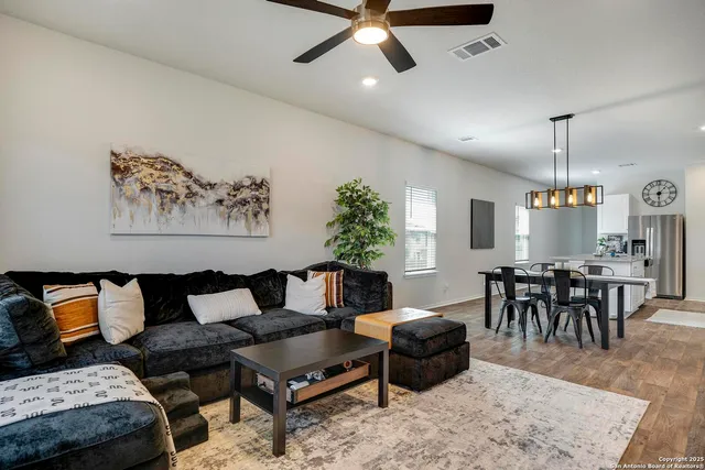 a living room with furniture and a dining table with wooden floor