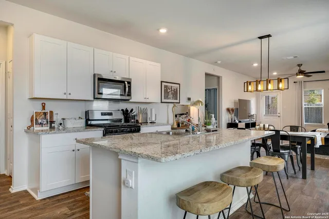 a kitchen with stainless steel appliances granite countertop a table chairs sink and cabinets