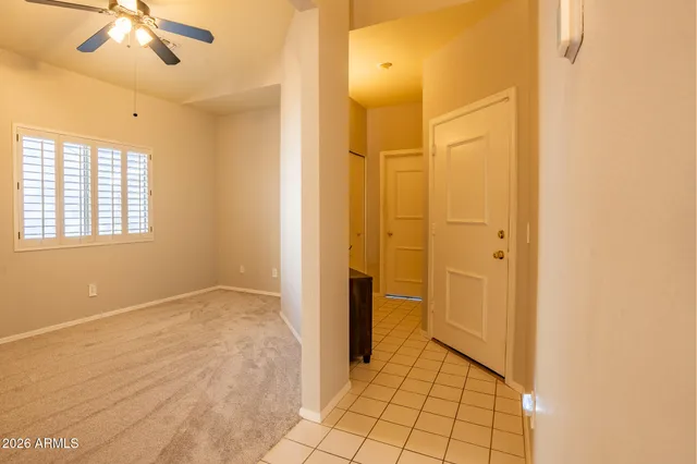a view of an empty room with window and chandelier fan