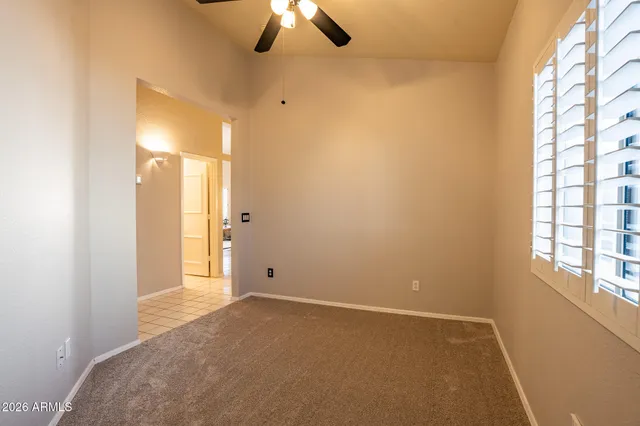 an empty room with chandelier fan and windows
