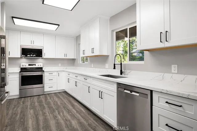a kitchen with kitchen island granite countertop white cabinets white appliances a sink and a window