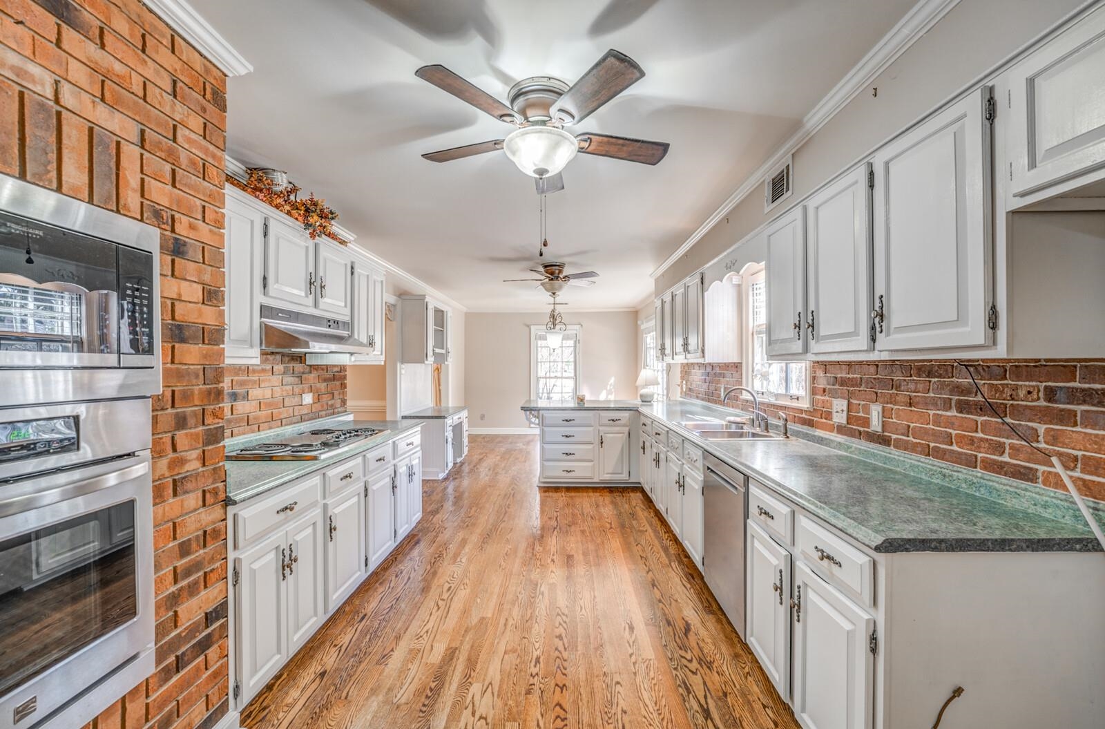 2997 Riverdale Road Memphis, TN 38119 - Photo 11 of 35 Kitchen featuring crown molding, stainless steel appliances, white cabinetry, light wood-style flooring, and a peninsula