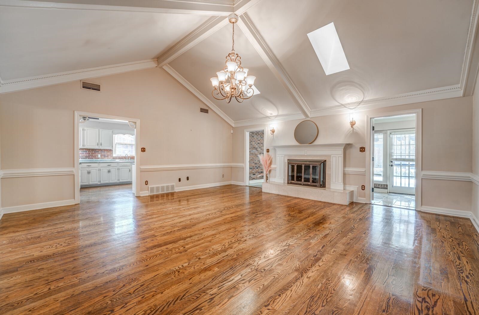 2997 Riverdale Road Memphis, TN 38119 - Photo 4 of 35 Unfurnished living room featuring light wood finished floors, hanging lights, a fireplace, and a skylight