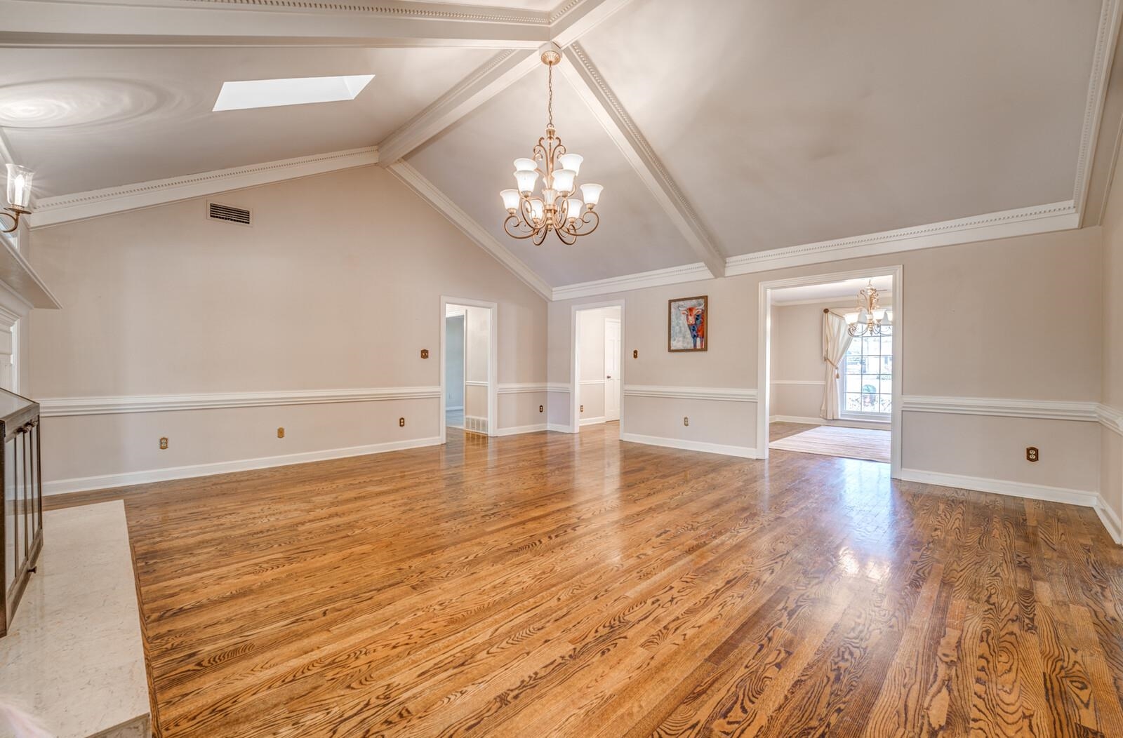 2997 Riverdale Road Memphis, TN 38119 - Photo 5 of 35 Unfurnished living room with hanging lights, a brick fireplace, light wood-type flooring, crown molding, and a skylight
