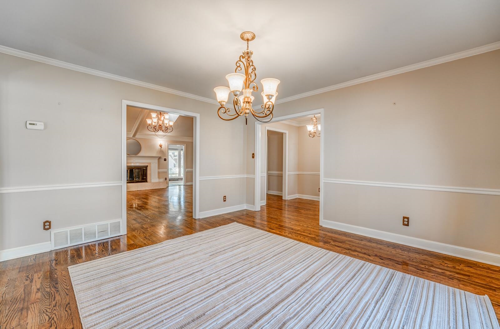 2997 Riverdale Road Memphis, TN 38119 - Photo 8 of 35 Spare room with hanging lights, a fireplace with raised hearth, wood finished floors, and crown molding