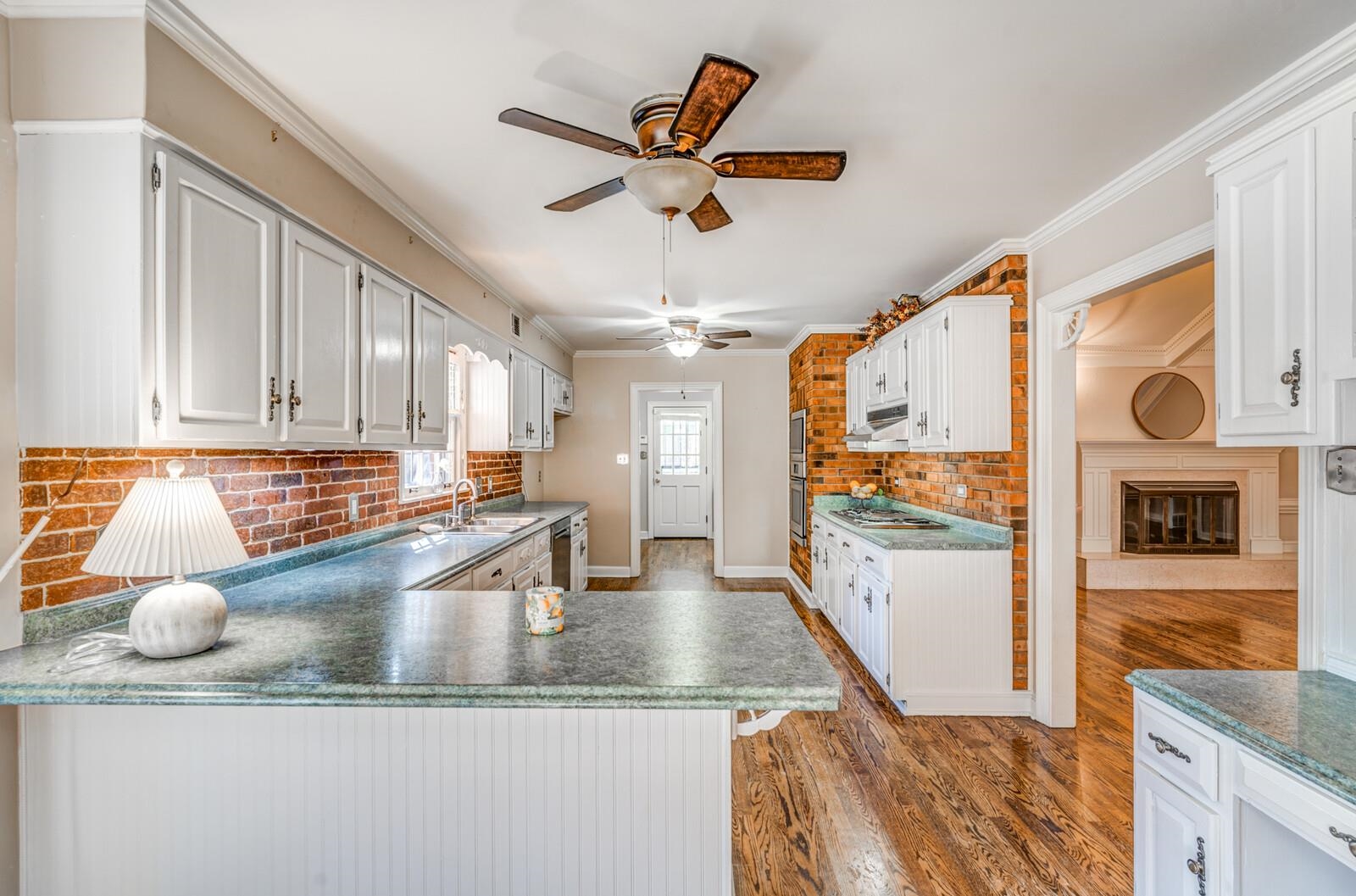 2997 Riverdale Road Memphis, TN 38119 - Photo 9 of 35 Kitchen with tasteful backsplash, white cabinets, ornamental molding, light wood finished floors, and a peninsula