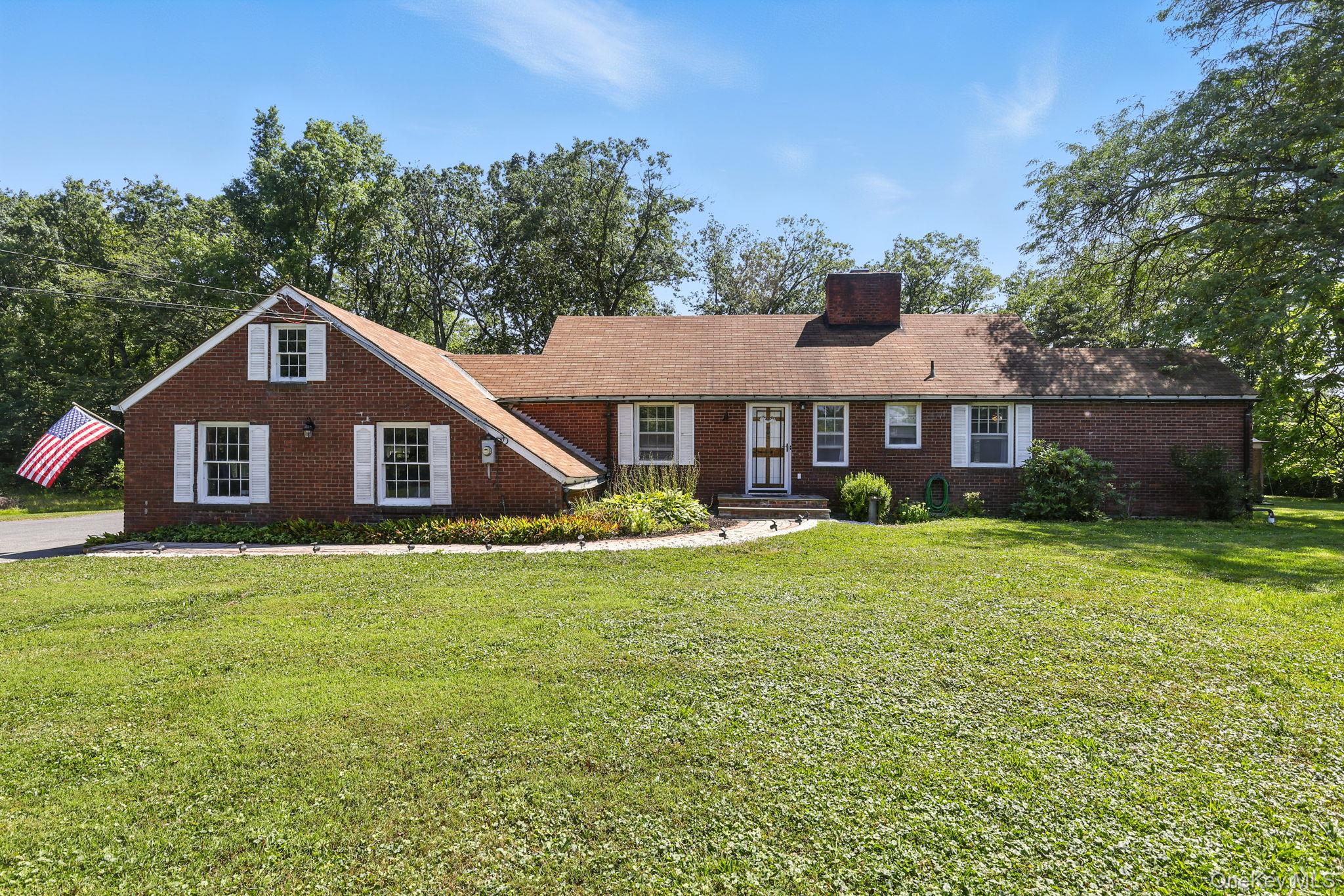 View of front of home featuring a front lawn, a chimney, and brick siding