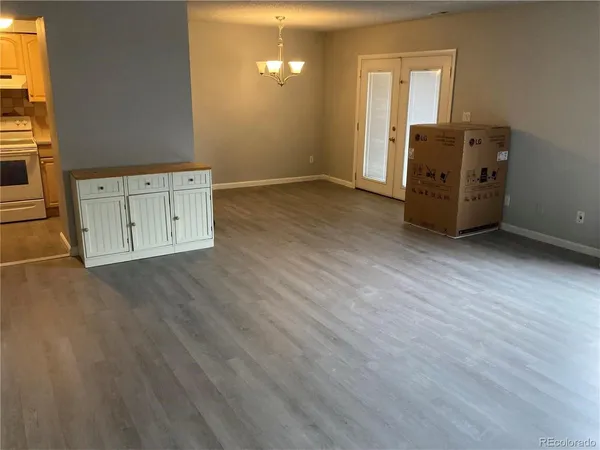 an empty room with wooden floor cabinet and windows