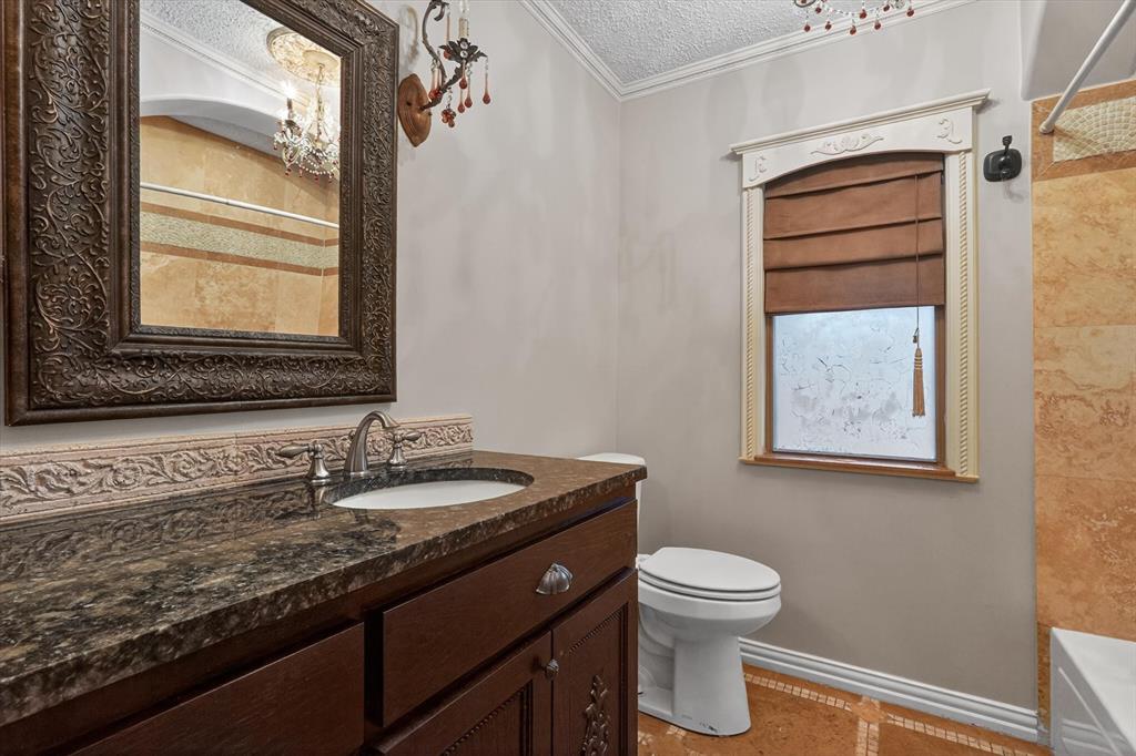 272 Lodge Road Coppell, TX 75019 - Photo 12 of 24 a bathroom with a granite countertop toilet a sink and a window