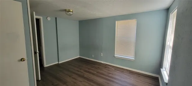 an empty room with wooden floor closet and windows