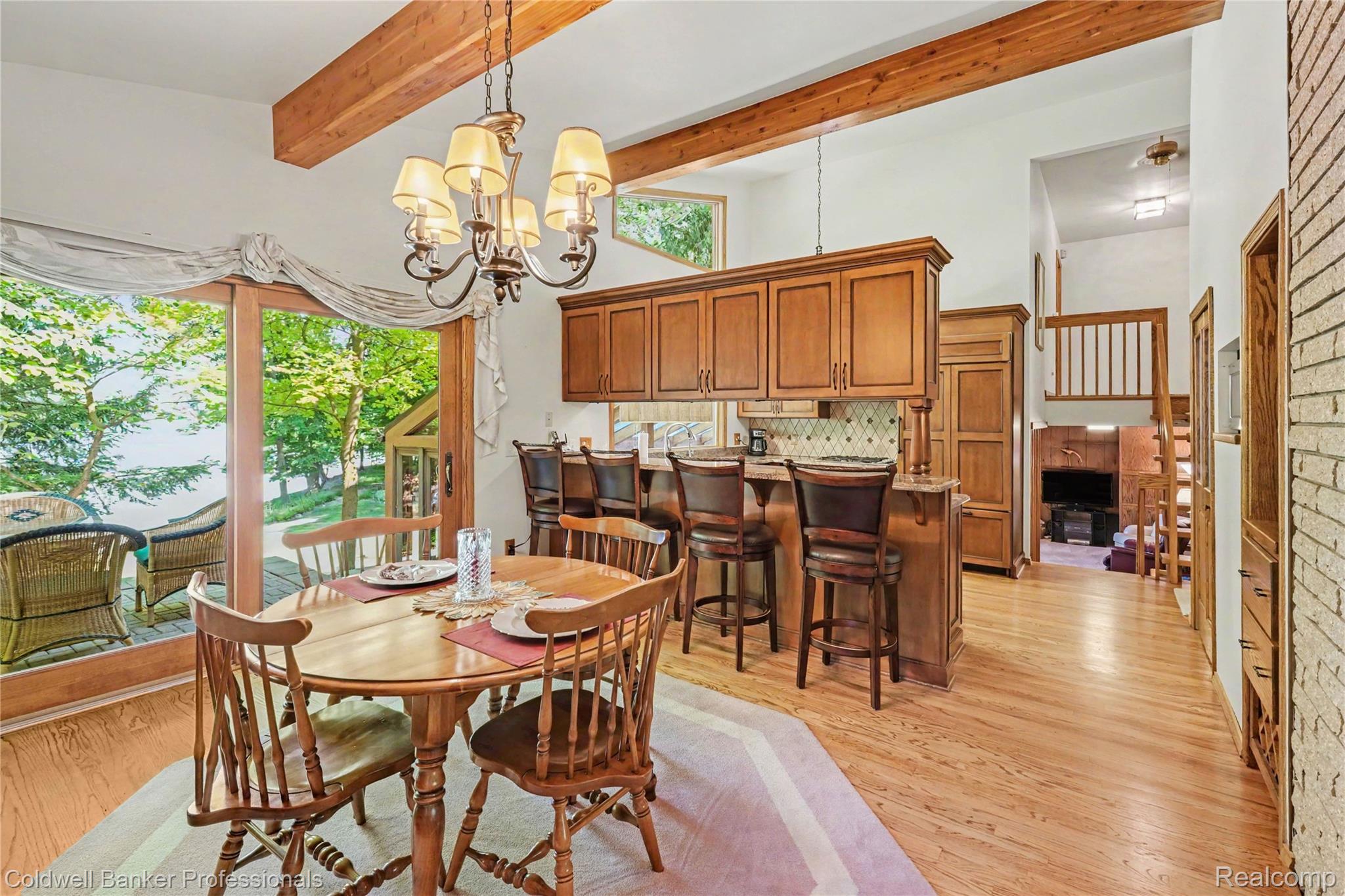 3583 Mitchell Road Metamora, MI 48455 - Photo 18 of 58 Open-concept dining space with wood-finish flooring, exposed wood ceiling beams, and a brass chandelier