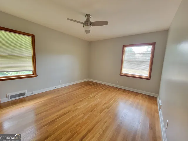 a view of an empty room with wooden floor and a window