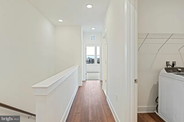 a view of a hallway with wooden floor and a bathroom