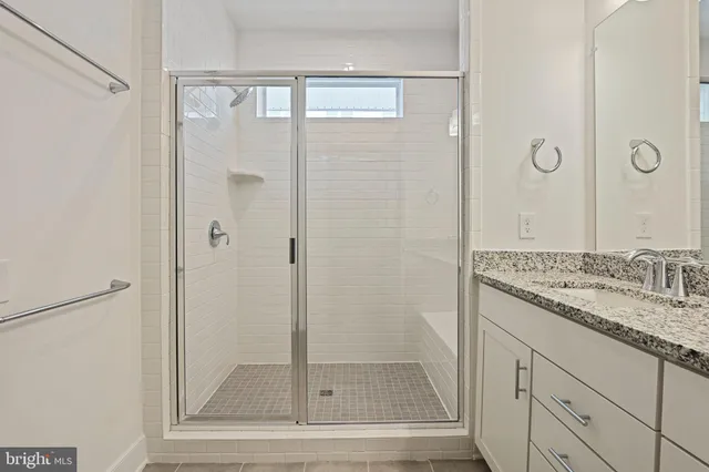 a bathroom with a granite countertop sink a mirror and shower