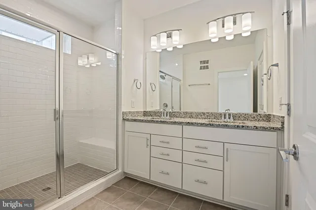 a bathroom with a granite countertop sink a mirror and a shower