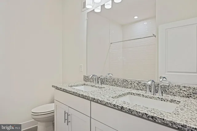 a bathroom with a granite countertop sink a toilet and a mirror