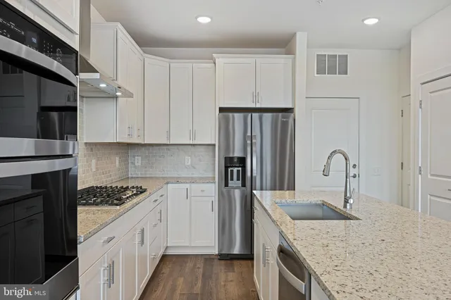 a kitchen with granite countertop a sink stainless steel appliances and cabinets