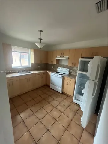 a kitchen with a sink a stove cabinets and a window