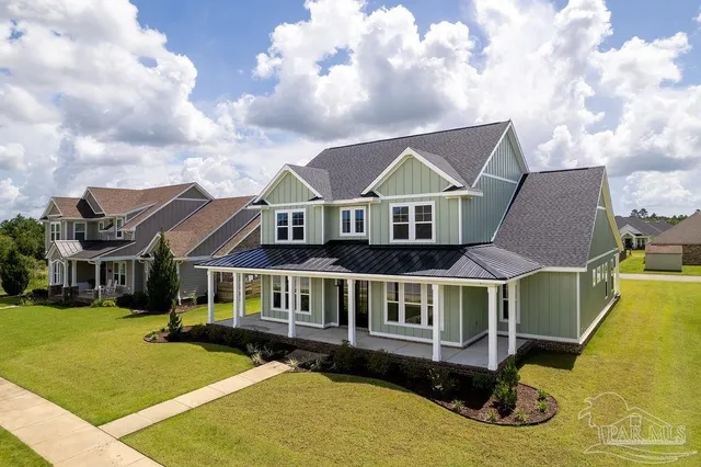 a white house with a large pool and lawn chairs with wooden floor