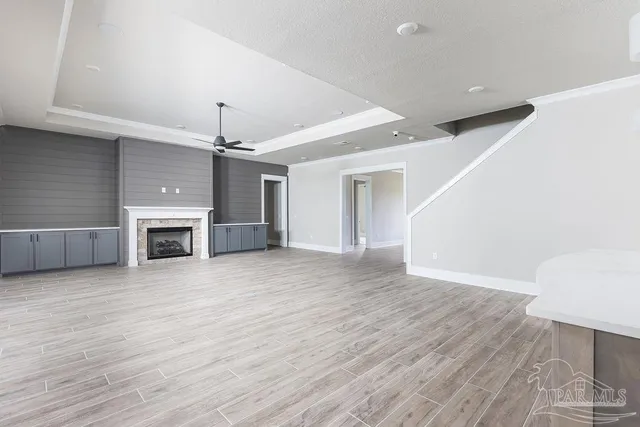 an empty room with wooden floor fireplace and windows